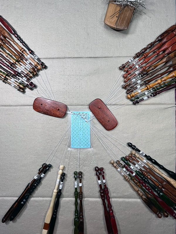 Pattern, bobbins, and threads to make a sample of the lace pattern. 