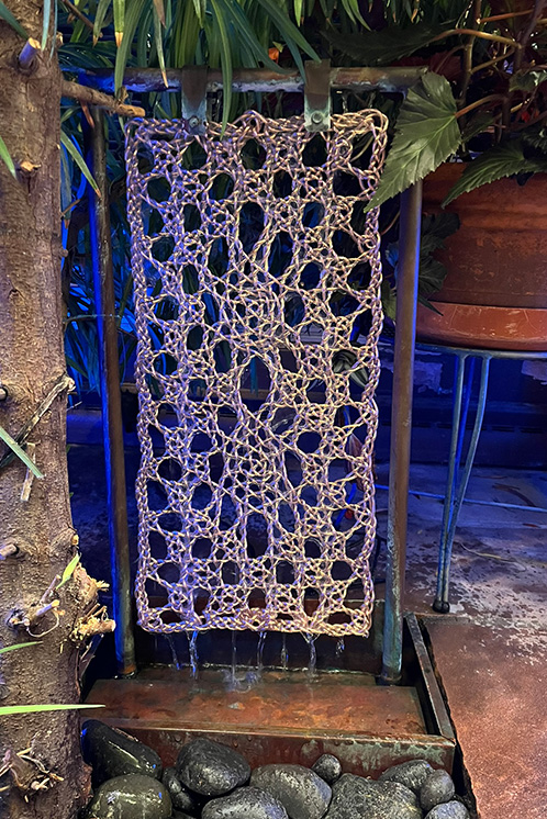 Lace installed in the fountain with water running over it. 