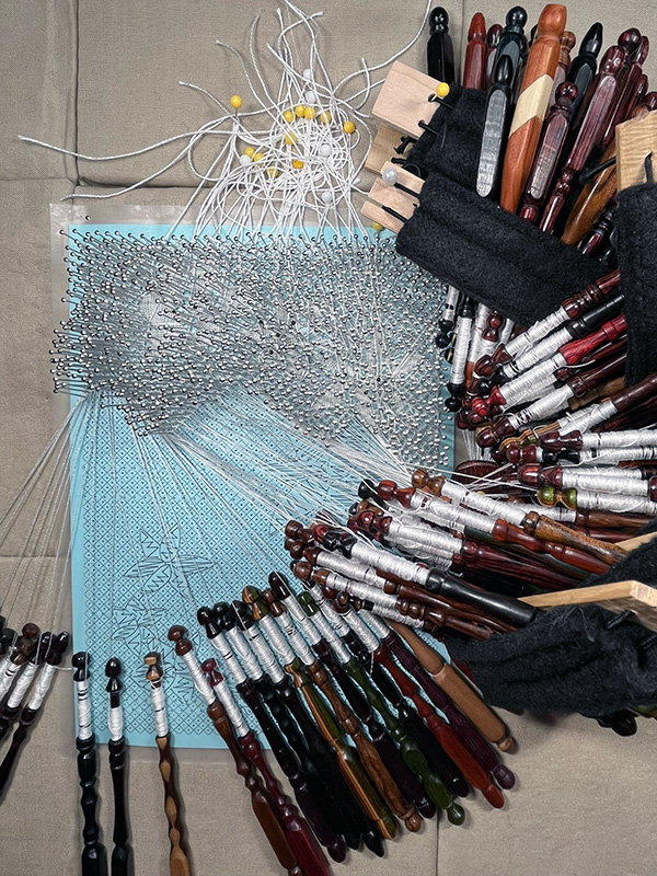 Disillusion Torchon bobbin lace in progress with bobbins arranged around the pillow.