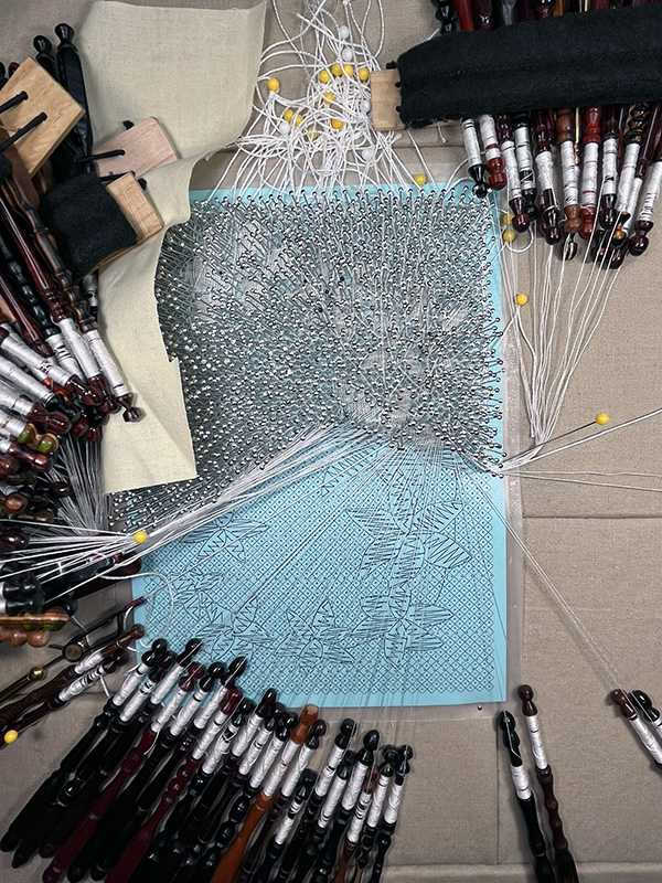 Working the floral Torchon bobbin lace pattern for Disillusion.