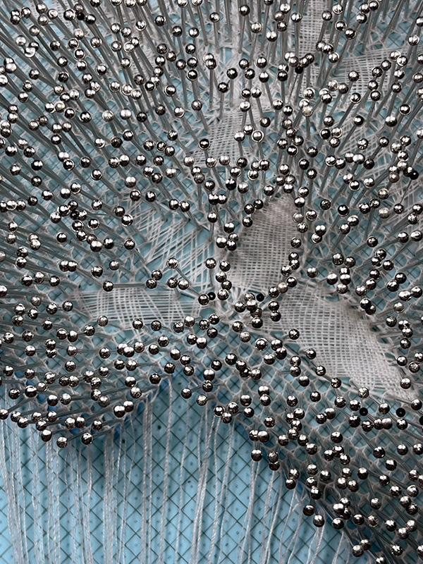 Cloth stitch trail extending beyond its gimp in Reality bobbin lace.