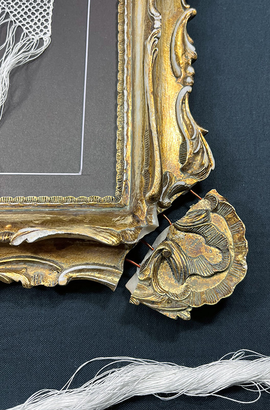 Broken corner of the ornate gold frame for Reality.