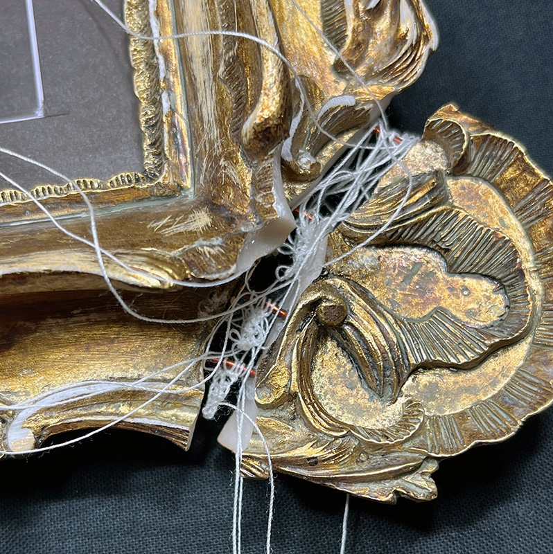 Broken frame corner reattached with copper wire and needle lace.