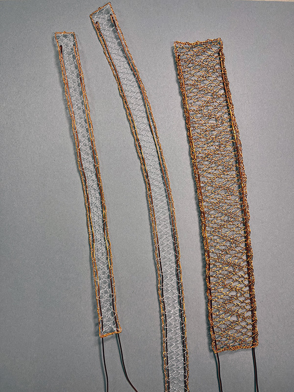 Three strips of lace made with fishing line and copper wire with heavy wire supports.
